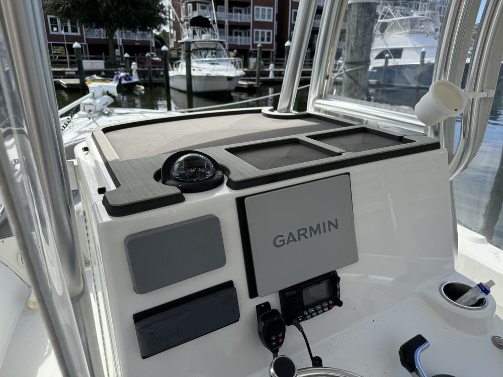 Custom-fit gray EVA foam dash pad on a center console helm, cut around the compass with built-in storage trays